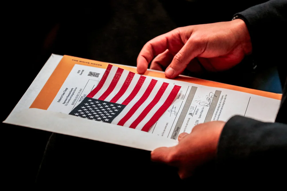 Abdullah Omar, from Iraq, holds his information packet and an American flag during a naturalization ceremony.