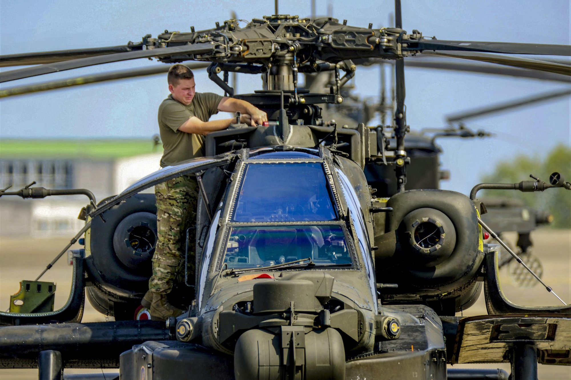 A U.S. Soldier with D Company, 1st Battalion, 3rd Aviation Regiment (Attack Reconnaissance), 12th Combat Aviation Brigade, conducts routine maintenance on a AH-64 Apache helicopter on Aug. 29, 2018, at Katterbach Army Airfield in Ansbach, Germany. Photo by Charles Rosemond