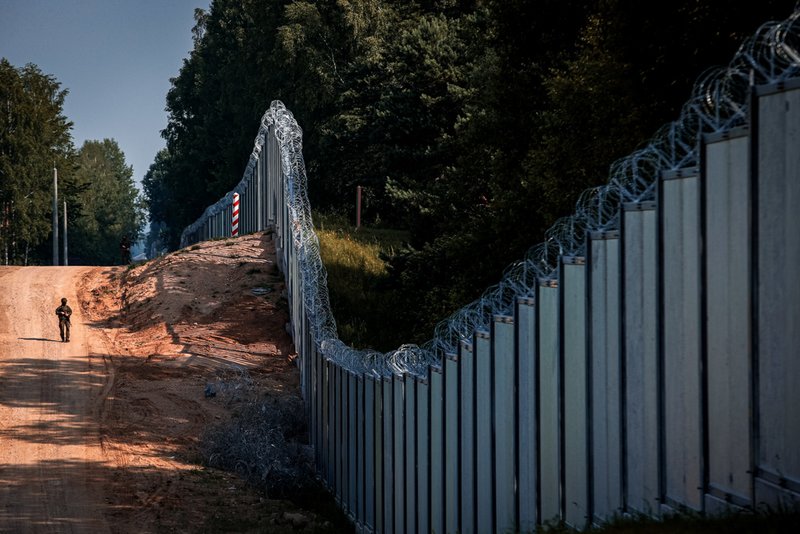 A Polish border guard patrols the area of a built metal wall on the border between Poland and Belarus.