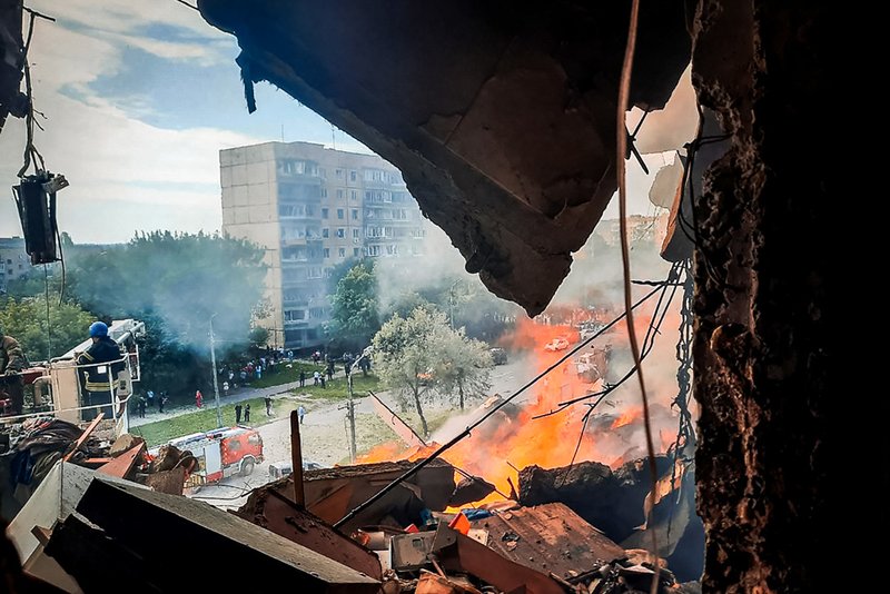 Emergency services work at a scene after a missile hits a multi-story apartment building.