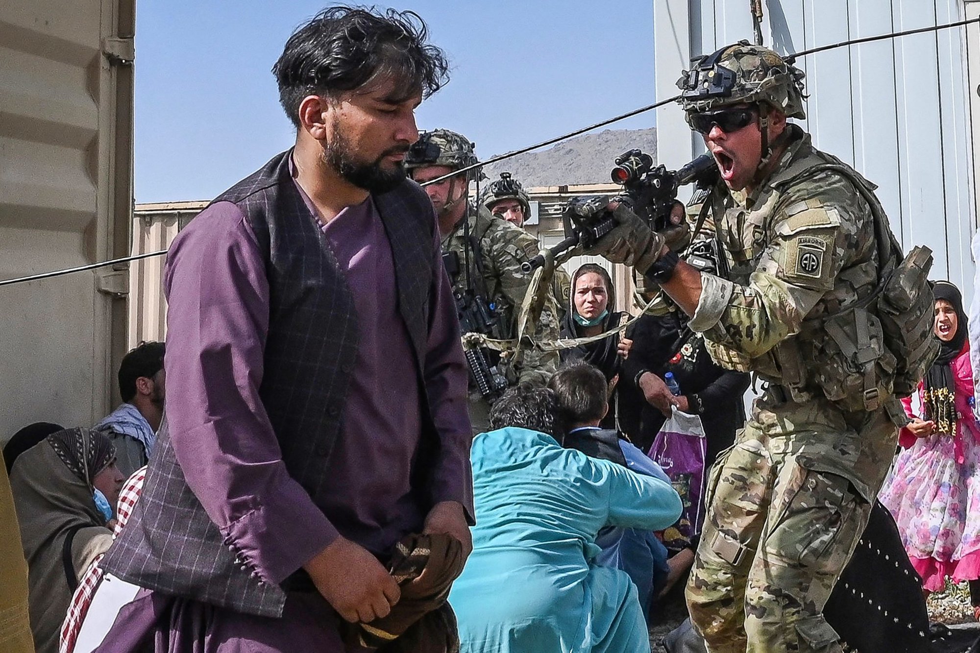 A US soldier points his gun toward an Afghan passenger at the Kabul airport in Kabul on Aug. 16, 2021, after a stunningly swift end to Afghanistan’s 20-year war, as thousands of people mobbed the city’s airport trying to flee the group’s feared hardline brand of Islamist rule. Photo by Wakil Kohsar/AFP.