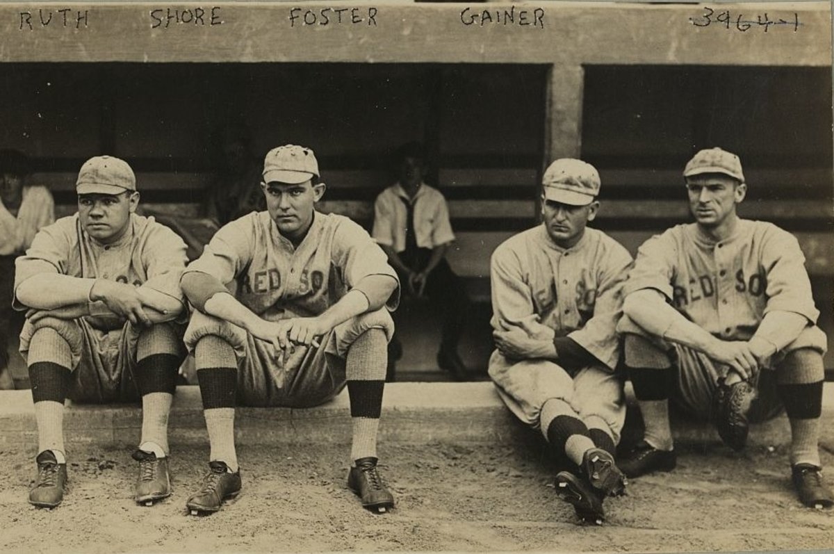 George Herman “Babe” Ruth, Ernest G. “Ernie” Shore, George “Rube” Foster, and Dellos “Del” Gainer, facing front, wearing Boston Red Sox baseball team uniforms, sitting on a low wall in front of a dugout, between 1915-1917, shortly before the Bambino’s fame would explode. Bain News Service photograph, now in the Library of Congress.