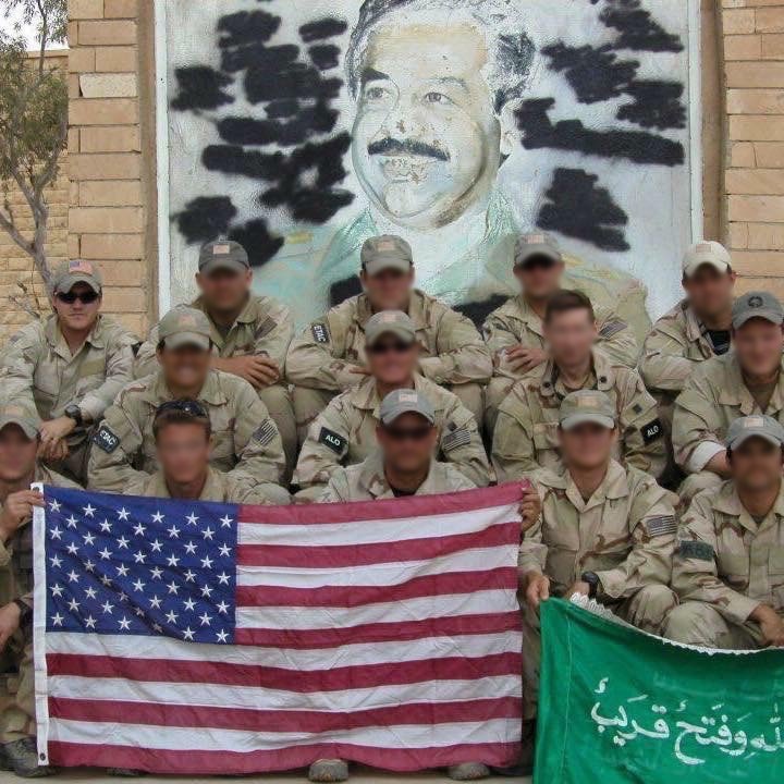 U.S. Air Force Staff Sergeant Ryan Shamrock poses with a group in front of a portrait of Saddam Hussein during the invasion of Iraq in 2003. Photo courtesy of Ryan Shamrock.