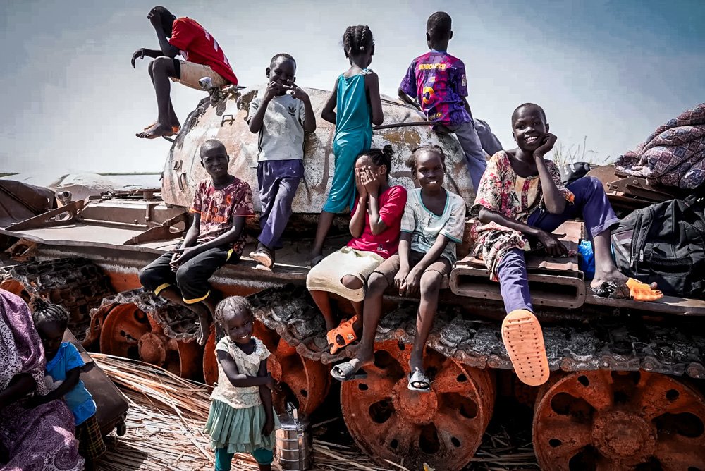Children set and play on the remains of a tank, at the river port in Renk, South Sudan.