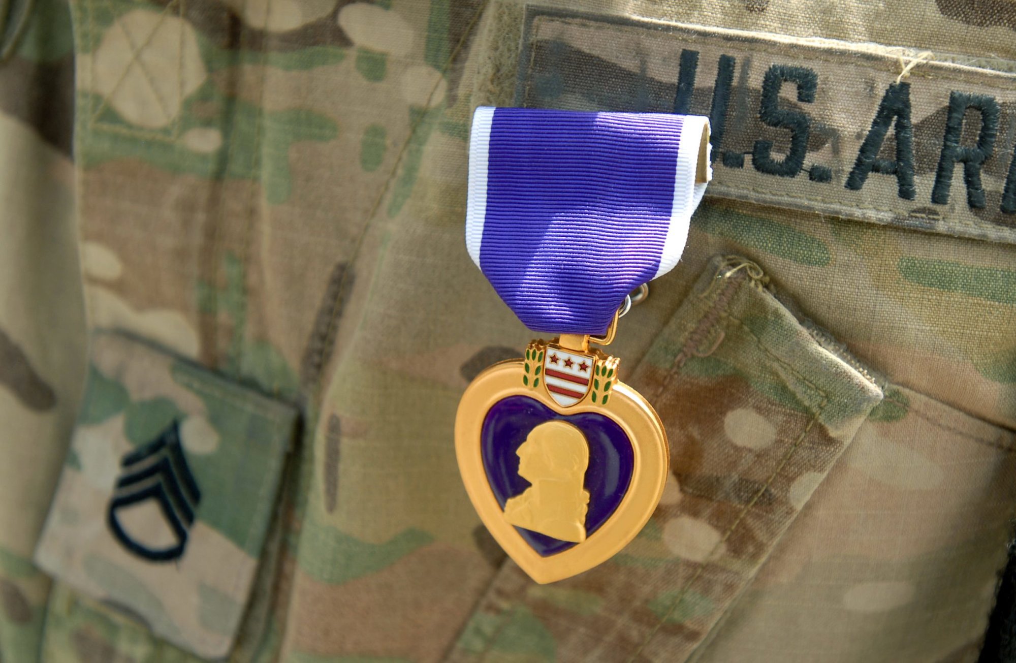 The Purple Heart medal stands out in contrast to the multicam uniform of Staff Sgt. Jason Ragucci, a public affairs broadcast specialist, assigned to the 1st Stryker Brigade Combat Team, 1st Armored Division during an award ceremony at Kandahar Airfield, Afghanistan, Aug. 6, 2013. Ragucci was awarded for wounds sustained during an improvised explosive device attack March 28, 2013, in the Maiwand district of Kandahar province. (U.S. Army National Guard photo by Staff Sgt. Scott Tynes/Released)