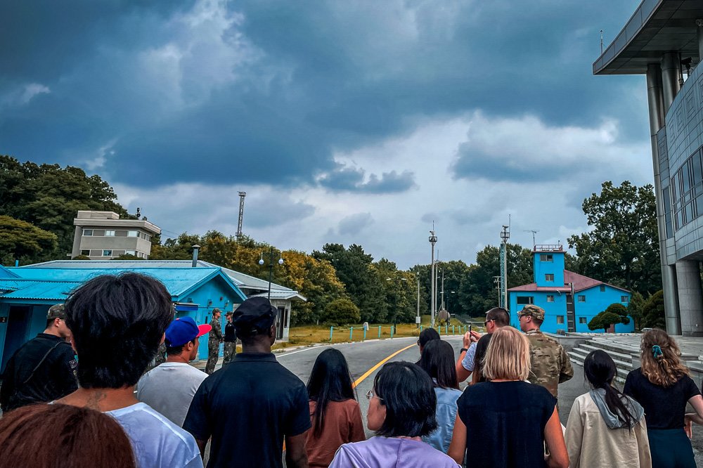 A group of tourists stand near a border station at Panmunjom in the Demilitarized Zone in Paju, South Korea, Tuesday, July 18, 2023. Not long after this photo was taken, Travis King, a U.S. soldier, pictured with dark blue shirt and dark cap, fourth left, bolted across the border and became the first known American detained in the North in nearly five years.