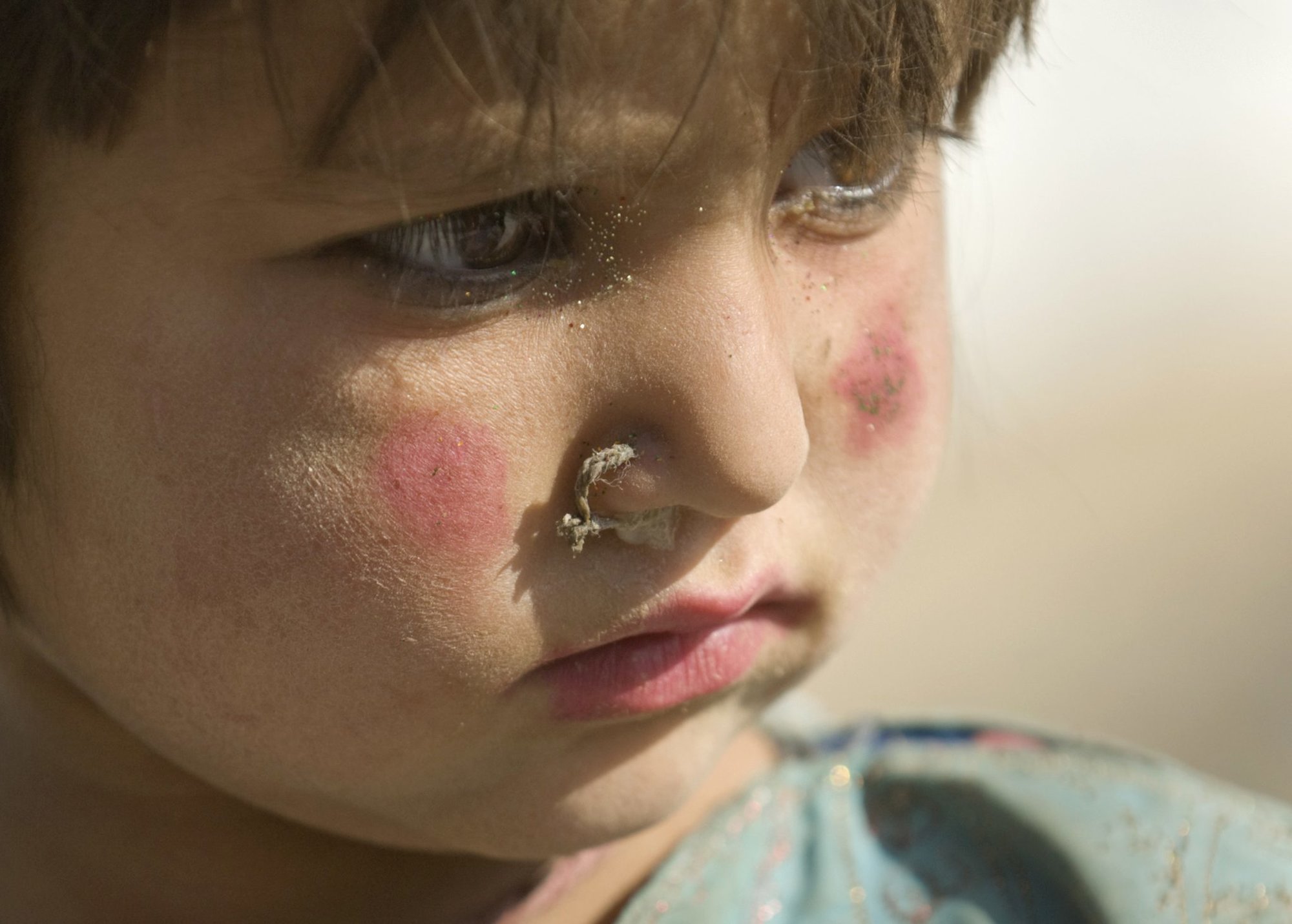 An Afghan girl waits to receive shoes and clothes during a humanitarian assistance visit to the Parwan Refugee Camp in Afghanistan in 2008. US Air Force photo by Master Sgt. Keith Brown.