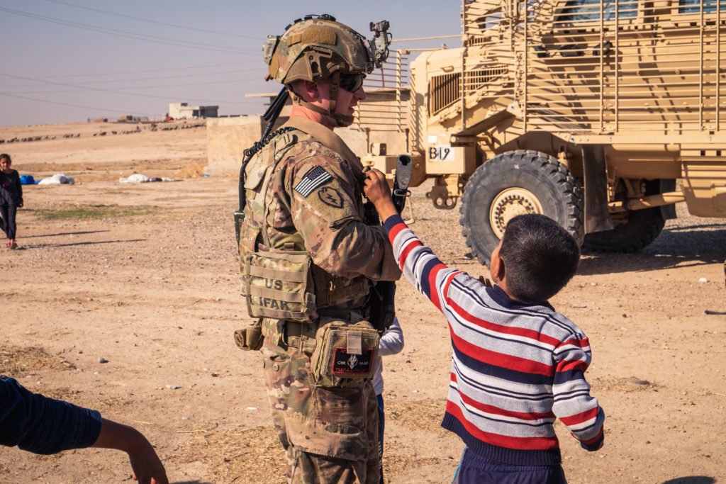 An Iraqi child grabs at Sgt. Mason’s gear and peppers him with questions.