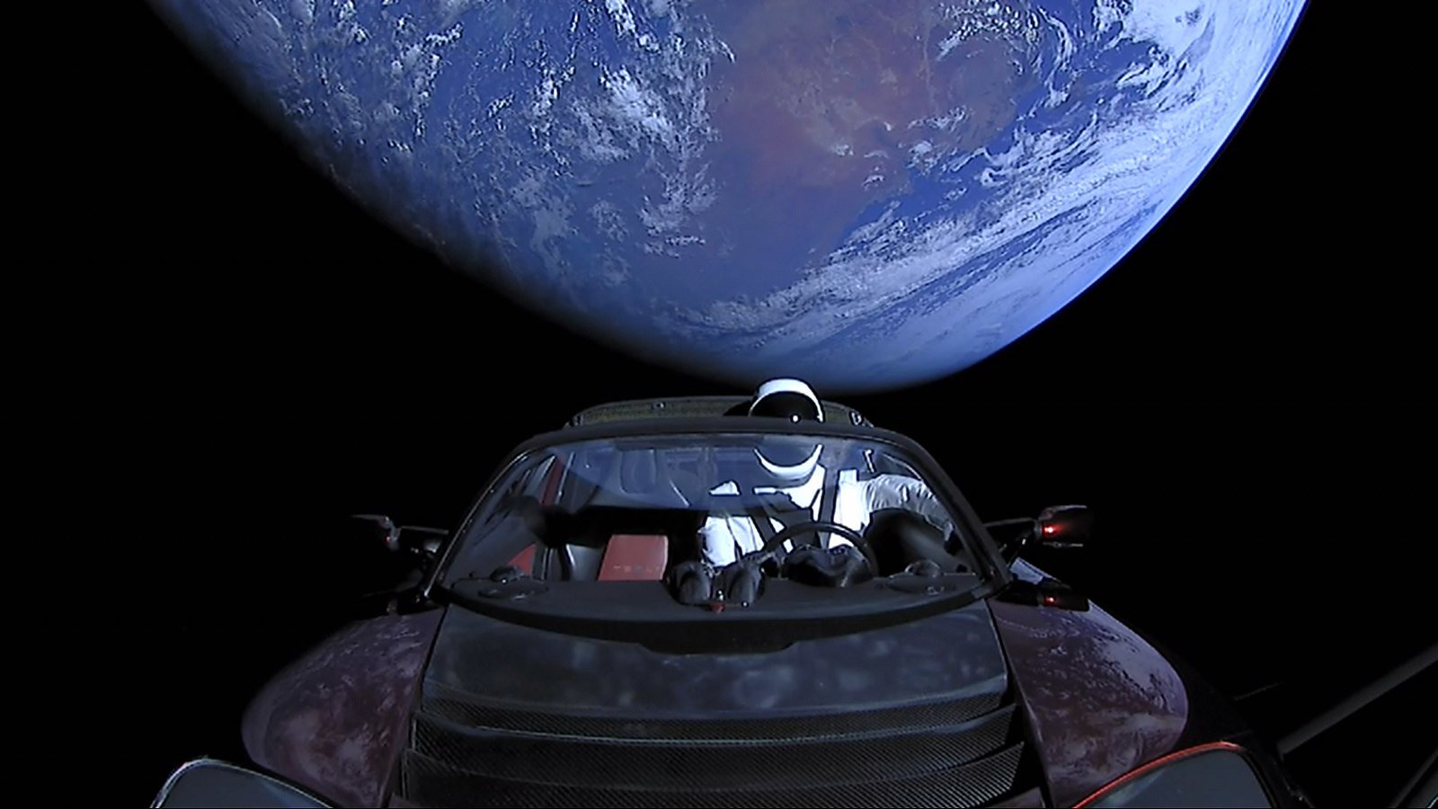 Elon Musk’s Tesla Roadster, with Earth in background. “Starman” mannequin wearing SpaceX Spacesuit in driving seat. Photo by SpaceX, via Wikimedia Commons.