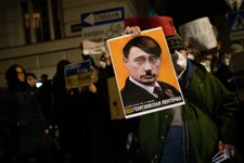 A demonstrator holds up a sign showing Russian President Vladimir Putin as Adolf Hitler as protesters gather outside the Russian Embassy to demonstrate against the invasion of Ukraine on Feb. 24, 2022, in Vienna, Austria. Photo by Thomas Kronsteiner/Getty Images.