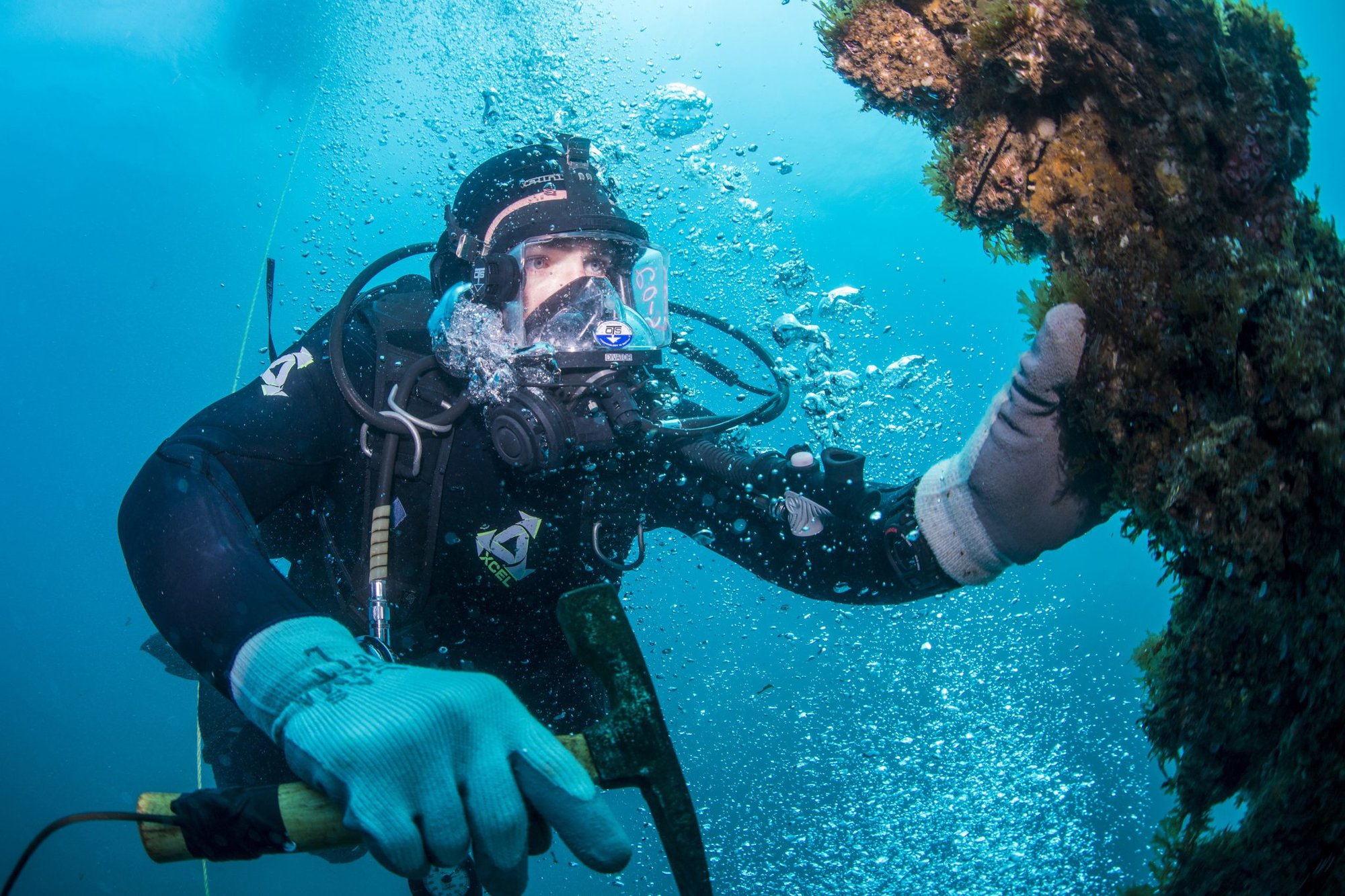 Petty Officer 2nd Class Matthew Bobinchak, an equipment operator assigned to an Underwater Construction Team, cleans growth off a buoy chain while participating in diver’s training off the coast of San Clemente Island, June 7, 2015.  US Navy photo by Mass Communication Specialist 2nd Class Daniel P. Rolston.
