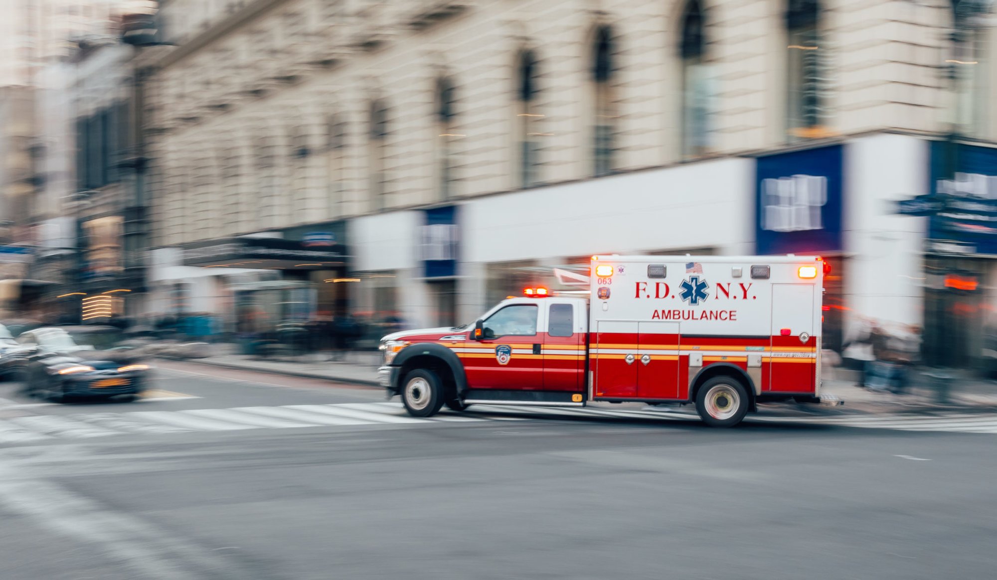 New York City, USA - March 18, 2017: FDNY Ambulance flashing lights siren blasting speed through midtown rush hour traffic in Manhattan.