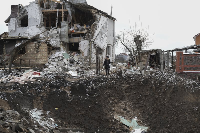 A woman stands on top of a crater next to a destroyed house after a Russian rocket attack in Hlevakha, Kyiv region, Ukraine, Thursday, Jan. 26, 2023. AP photo by Roman Hrytsyna.