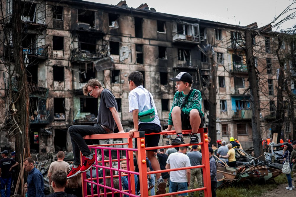 Children look at the scene of the latest Russian rocket attack that damaged a multi-story apartment building.