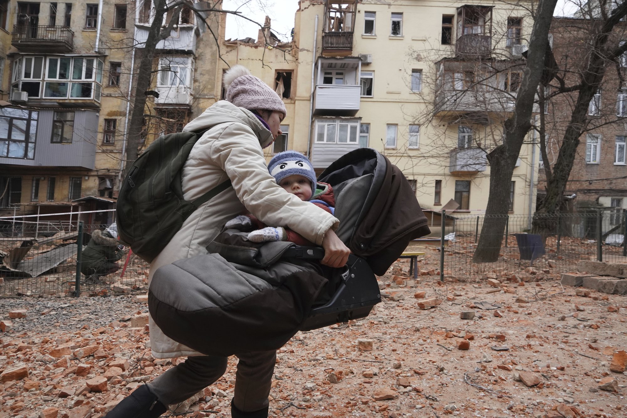 A woman carries her child as they evacuate from a residential building which was hit by a Russian rocket at the city center of Kharkiv, Ukraine, Monday, Jan. 30, 2023. Russian shelling killed at least five people and wounded 13 others during the previous 24 hours, Ukrainian authorities said Monday as the Kremlin’s and Kyiv’s forces remained locked in combat in eastern Ukraine. AP photo by Andrii Marienko.