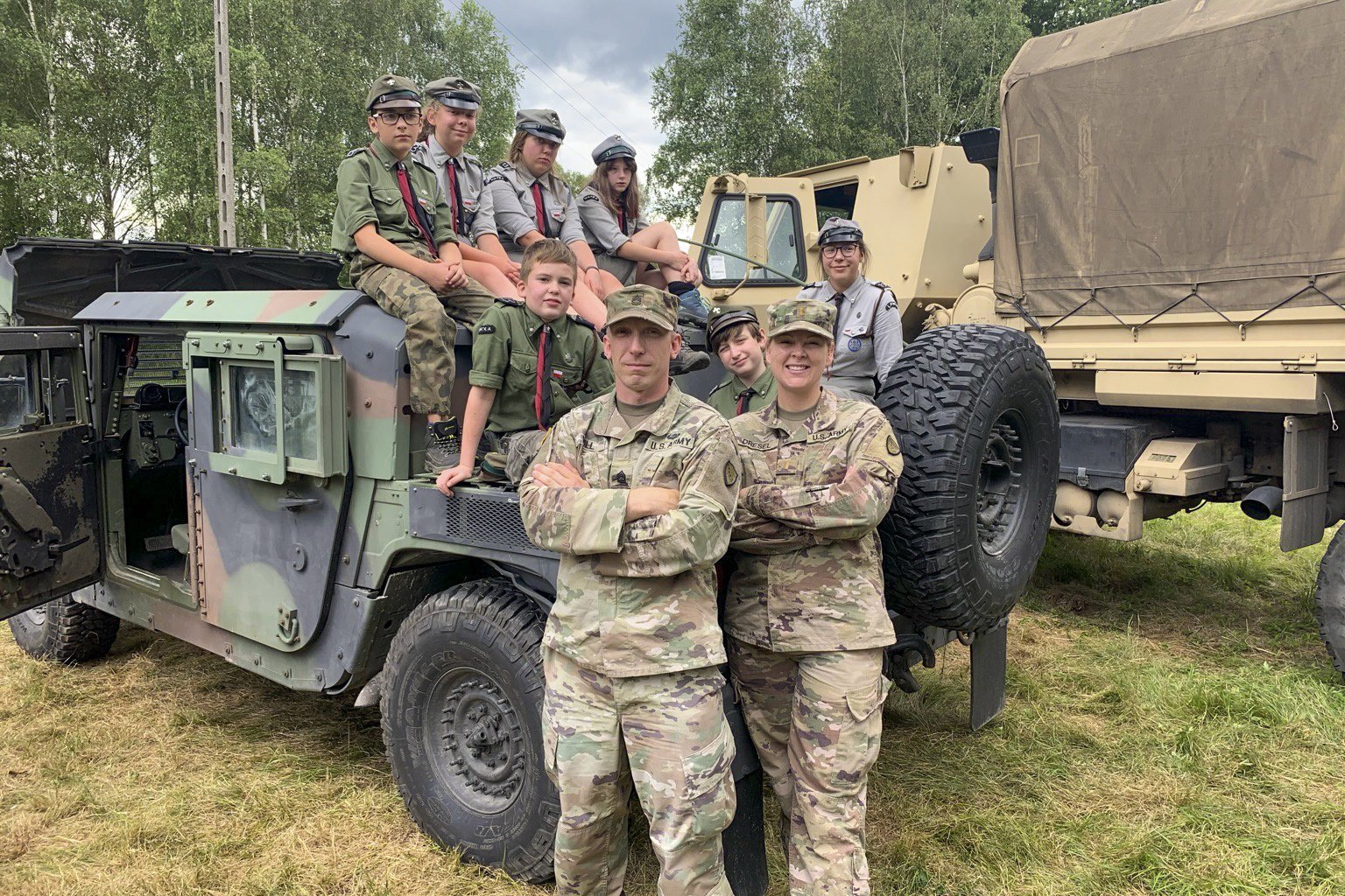 U.S. Army Sgt. 1st Class Dayton Will, left, Forward Operating Site Świętoszów deputy mayor and 2nd Lt. Balinda Dresel, FOS Świętoszów mayor, both with the Alaska National Guard’s 297th Regional Support Group, pose for a picture with Polish scouts at Camp Watra near Osieczow, Poland, July 17, 2020.  The Alaska Guardsmen and Reservist with the 266th Ordinance Company, out of Puerto Rico, and Bravo Company, 418th Civil Affairs Battalion, out of Missouri, learned about the history and values of the Polish scouting organization while sharing their units’ missions and high-mobility multipurpose wheeled and medium tactical vehicles that are assigned to nearby FOS Świętoszów.