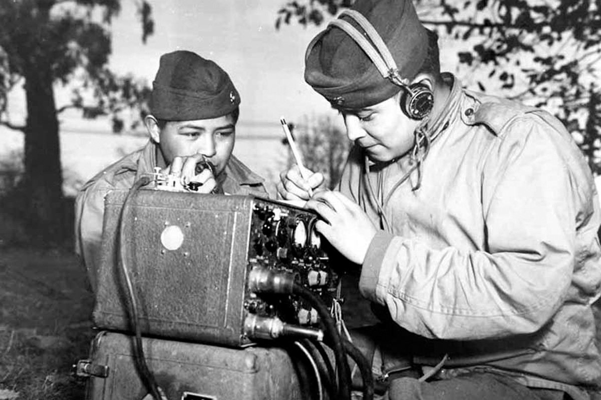Pfcs. Preston Toledo and Frank Toledo, both Navajo Code Talkers and cousins, relay orders in the Navajo language on a field radio, July 7, 1943. They were attached to a Marine artillery regiment in the South Pacific. US Marine Corps photo.