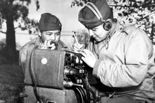 Pfcs. Preston Toledo and Frank Toledo, both Navajo Code Talkers and cousins, relay orders in the Navajo language on a field radio, July 7, 1943. They were attached to a Marine artillery regiment in the South Pacific. US Marine Corps photo.