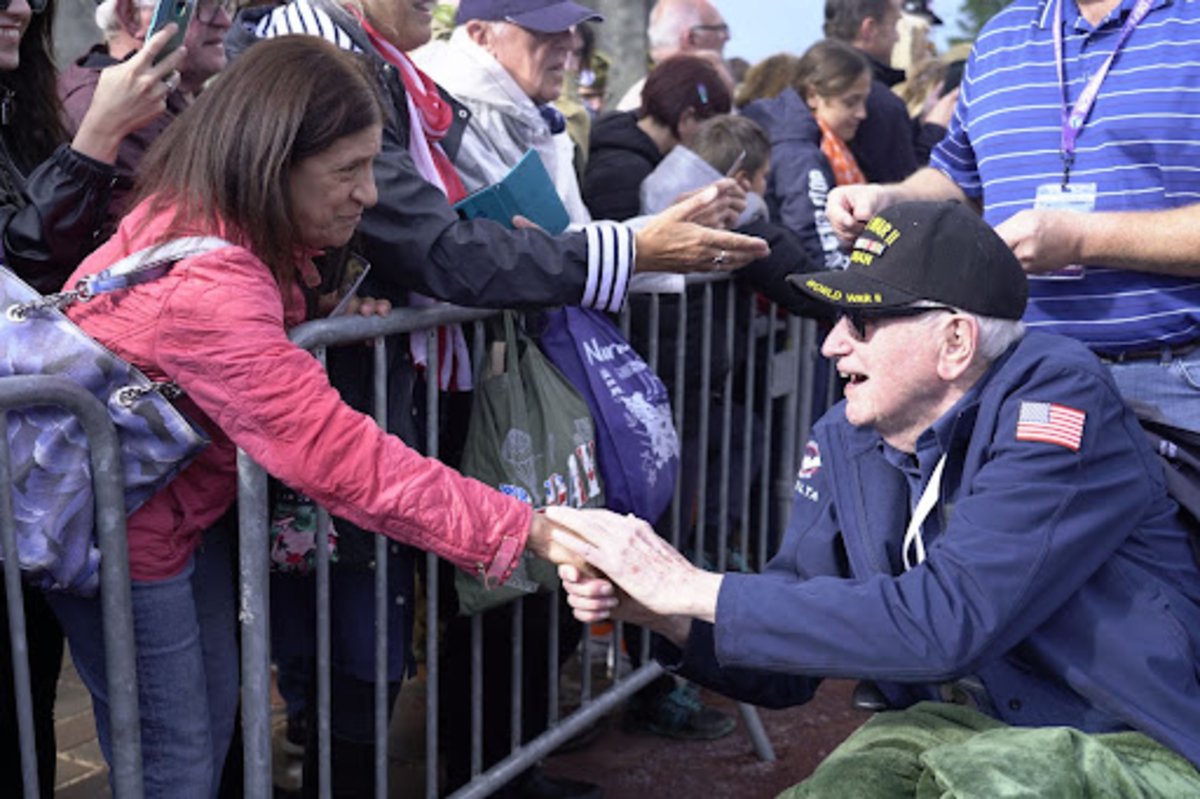 Raymond Dawkins, 96, from Newberry, S.C., shakes a woman’s hand during a parade held in Sainte-Mère-Église, France, on June 5, 2022, during the town’s D-Day celebration. Photo by Noelle Wiehe/ Coffee or Die Magazine.
