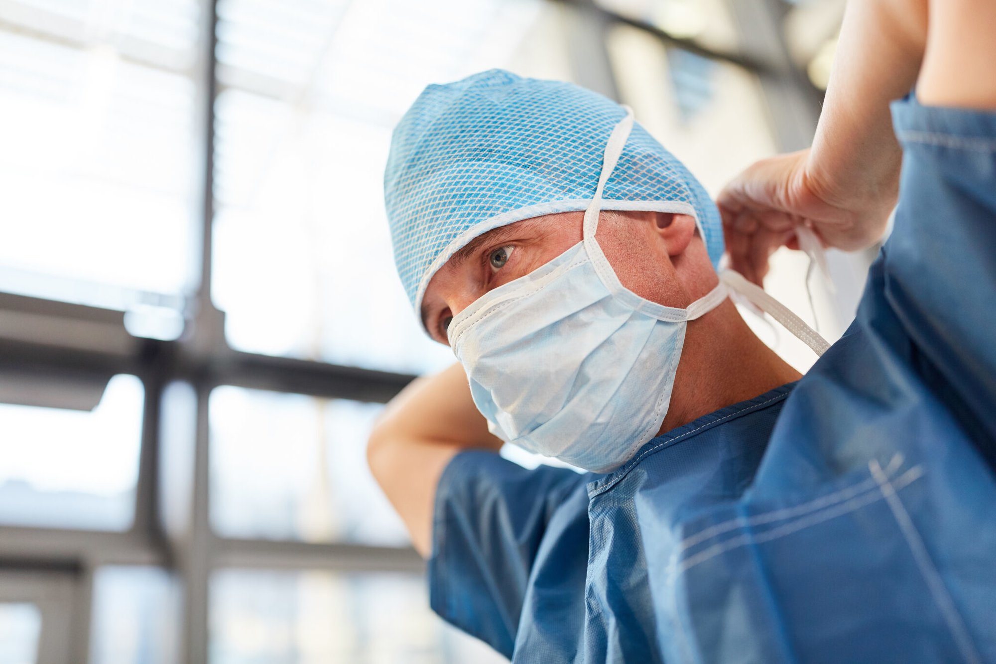 Surgeon in blue surgical gown binds the mouthguard for an emergency