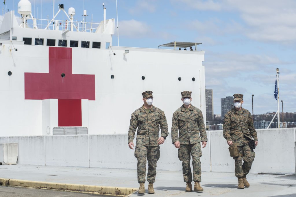 U.S. Marine Corps Lance Cpls. Andrew Hatmaker, left, and Travis Passaro, middle, and Hospital Corpsman Zachary Faull, assigned to II Marine Expeditionary Force, walk along Pier 90 April 2, 2020, as part of a Marine security detachment supporting the Military Sealift Command hospital ship USNS Comfort (T-AH 20). Comfort deployed to New York in support of the nation’s COVID-19 response efforts and will serve as a referral hospital for non-COVID-19 patients currently admitted to shore-based hospitals. This allows shore-based hospitals to focus their efforts on COVID-19 cases. One of the Department of Defense's missions is Defense Support of Civil Authorities. DoD is supporting the Federal Emergency Management Agency, the lead federal agency, as well as state, local and public health authorities in helping protect the health and safety of the American people. U.S. Navy photo by Mass Communication Specialist 2nd Class Adelola Tinubu/Released.