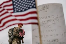A member of the 3rd US Infantry Regiment, also known as The Old Guard, places flags in front of each headstone for "Flags-In" at Arlington National Cemetery in Arlington, Thursday, May 25, 2023, to honor the nation's fallen military heroes ahead of Memorial Day. AP photo by Andrew Harnik.