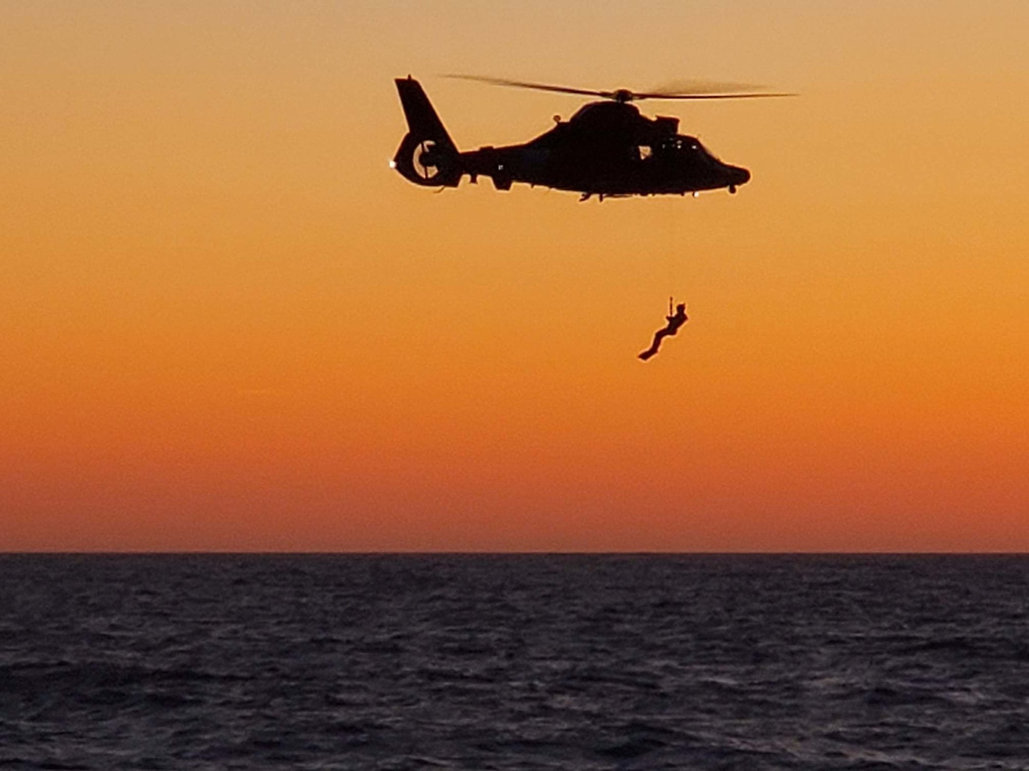 A Coast Guard rescue swimmer is hoisted into a Coast Guard Sector  North Bend MH-65D Dolphin helicopter during training near Newport, Oregon, April 30, 2019. New 5g cell phones may interfere with radar altimeters which pilots often rely on for hovering. US Coast Guard photo.