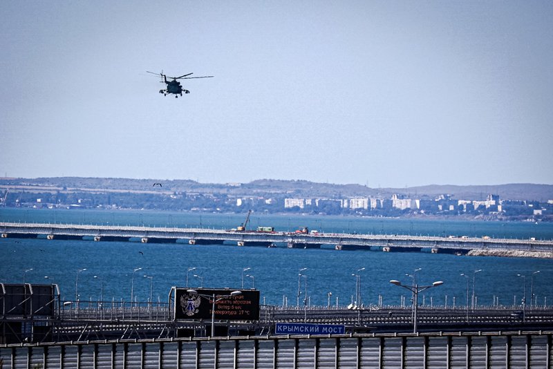 A Russian military helicopter flies over damaged parts of an automobile link of the Crimean Bridge connecting Russian mainland and Crimean peninsula over the Kerch Strait.