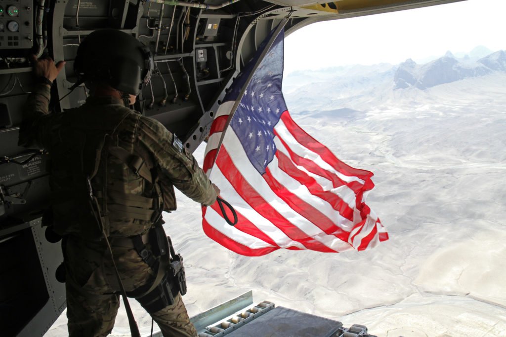 Sgt. Michael Misheff, CH-47F Chinook helicopter chew chief for Task Force Flying Dragons, flies the American flag over southern Afghanistan Aug. 28. Task Force Raptor pilots and crew chiefs fly American flags to present with certificates to service members as part of aviation tradition. Photo courtesy of the Department of Defense.