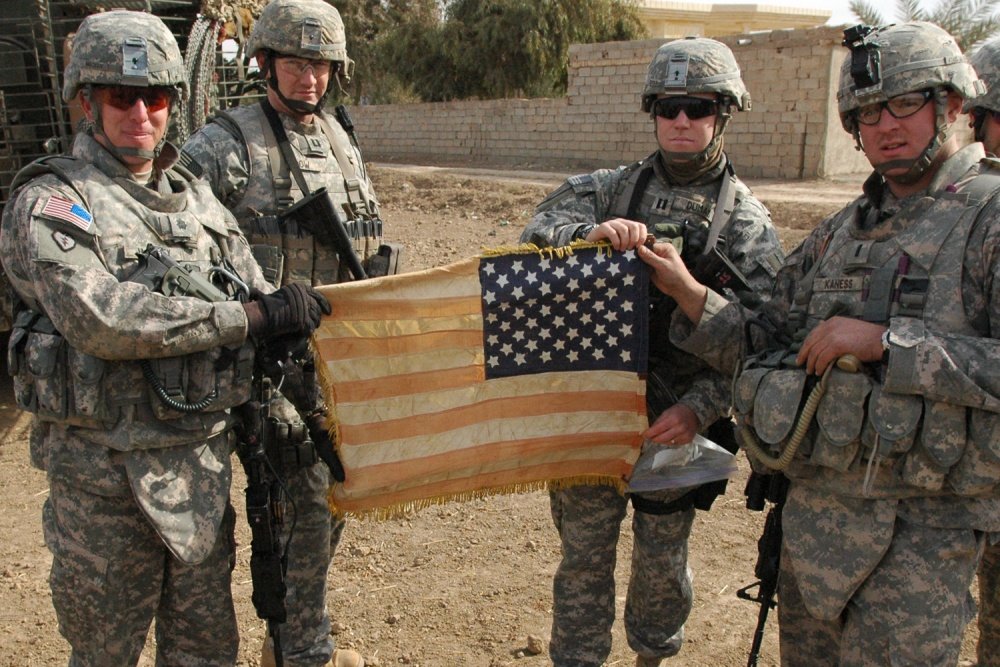 From left to right: San Bernardino, Calif., native Lt. Col Thomas H. Mackey, commander of the 2nd Squadron, 14th Cavalry Regiment, 2nd Stryker Brigade Combat team, ‘Warrior,’ 25th Infantry Division, Leavenworth, Kansas, native Capt. Nathaniel Crow, commander, Troop B, 2nd Squadron, 14th Cavalry Regiment, 2nd Stryker Brigade Combat Team, ‘Warrior,’ 25th Infantry Division, Green Bay, Wis., native Capt. Joseph Dumas, and Rochester, N.Y., native, 1st Lt. Michael Kaness, display the Hoe battle flag during a patrol, Jan. 22. They hold the flag in reverse to symbolize the way Soldiers wear the flag on their right shoulder. Crow said the flag represents a ‘lineage of warriors.’  Photo by Sgt. Aaron Rosencrans via DVIDS.