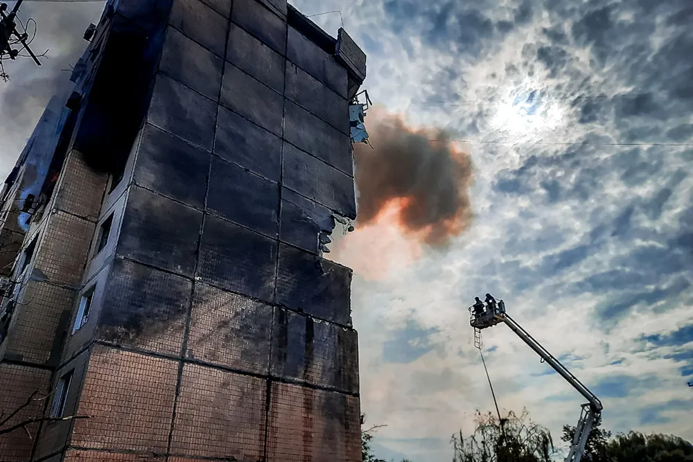 Emergency services work at a scene after a missile hits a multi-story apartment building.