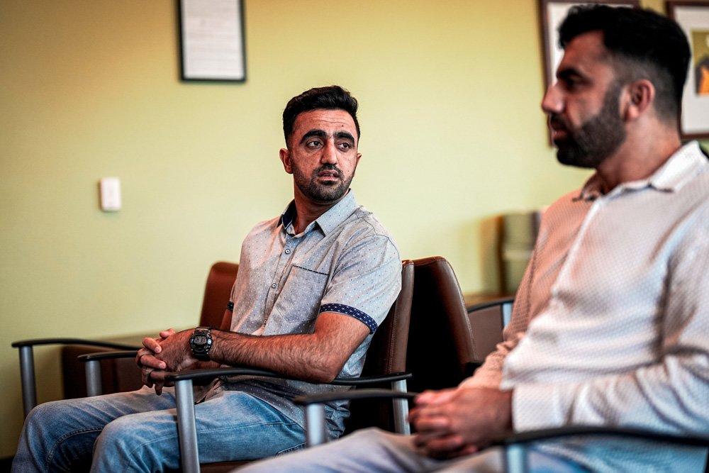 Abdul Wasi Safi, left, listens to his brother Samiullah while sitting in a dentist's waiting room.