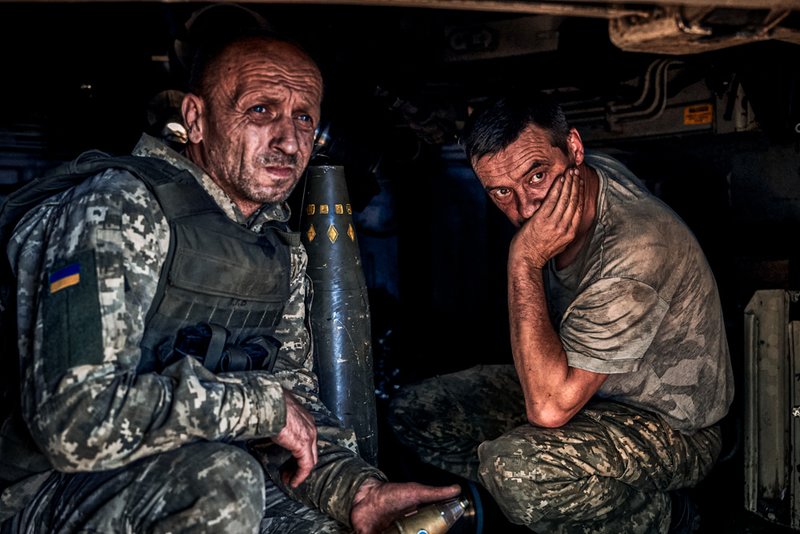 Ukrainian soldiers sit inside self-propelled howitzer.