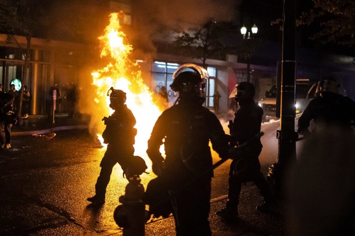 Portland police officers walk past a fire started by a Molotov cocktail thrown at them on Sept. 23, 2020. Photo by Nathan Howard/Getty Images.