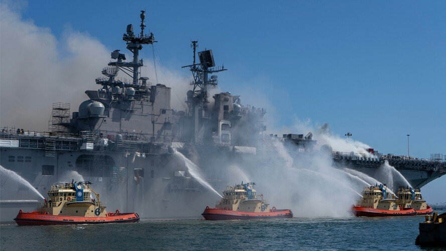 US Navy sailors and federal firefighters battle a blaze sweeping the amphibious warship Bonhomme Richard (LHD 6) at Naval Base San Diego, on July 12, 2020. Bonhomme Richard had been going through a maintenance availability that began in 2018 when the fire destroyed the vessel. US Navy photo by Mass Communication Specialist 3rd Class Christina Ross.