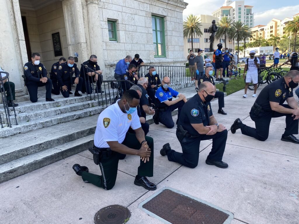 Demonstrators and police chiefs from Miami Dade County kneel and say a prayer. Photo courtesy of Twitter/Franklin White.