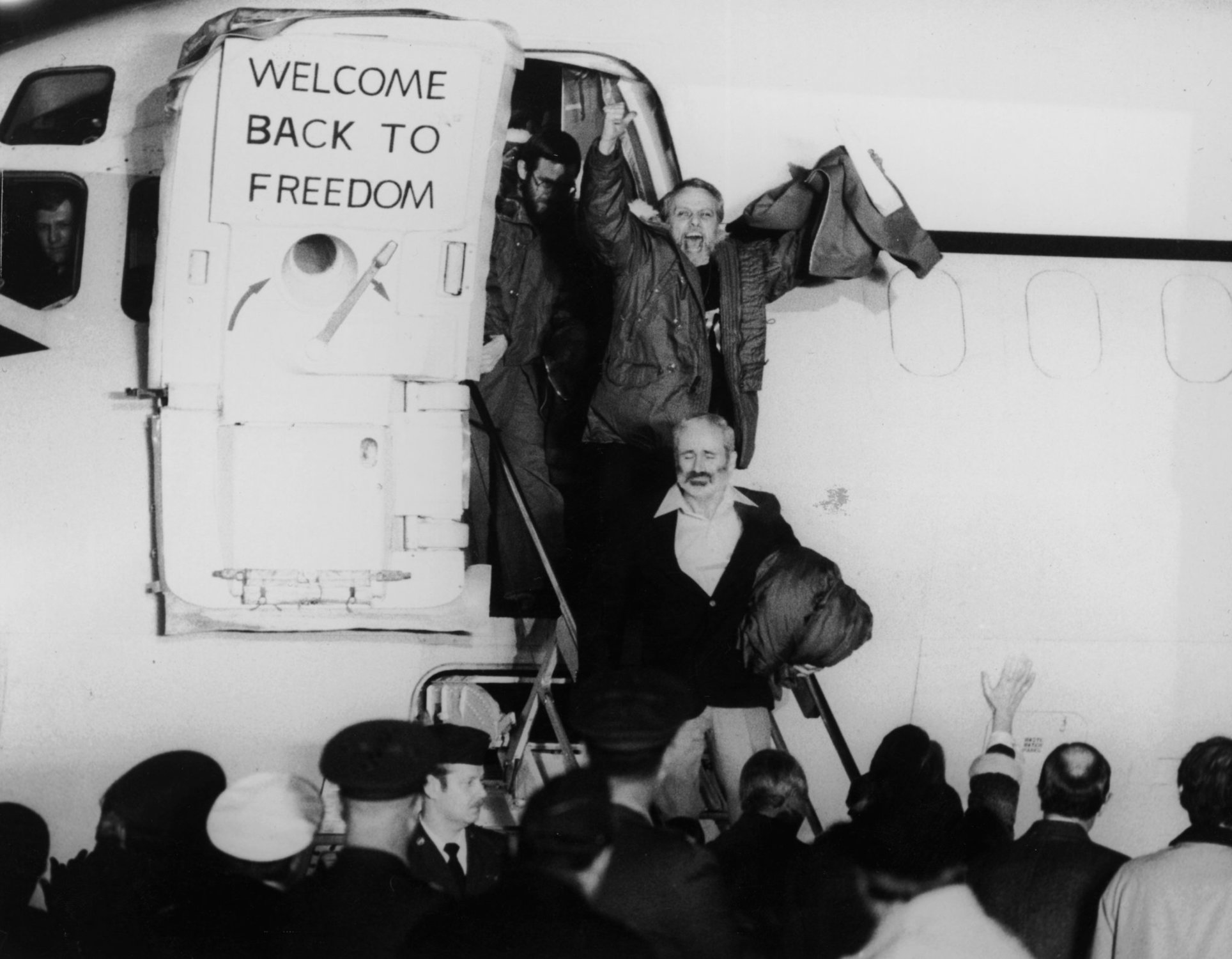 January 1981:  United States hostages departing an airplane on their return from Iran after being held for 444 days. One of the hostages is waving his fists in the air, and a sign on the plane door says, ‘Welcome Back to Freedom’.  (Photo by Express/Express/Getty Images)