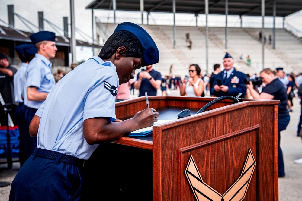Airman 1st Class D'elbrah Assamoi, from Cote D'Ivoire, signs her U.S. certificate of citizenship after the Basic Military Training Coin Ceremony.