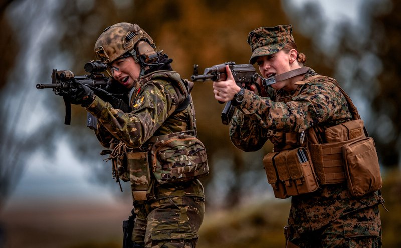 A Romanian female soldier, left, and a US Marines female counterpart aim after switching weapons