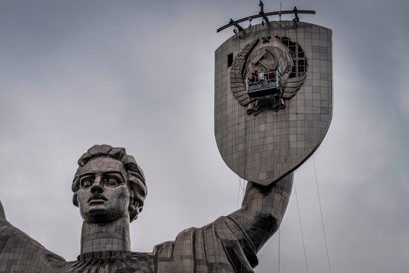 Workers prepare to remove a Soviet emblem from the shield of the Motherland Monument.