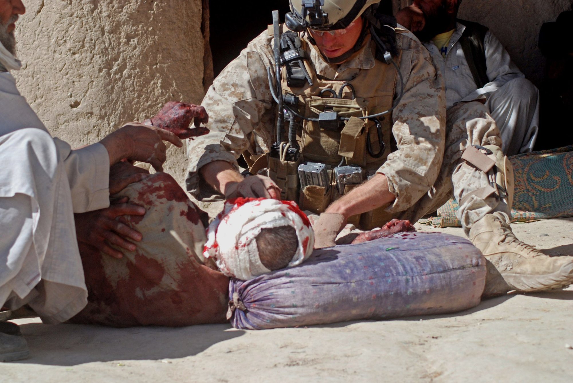 A Navy hospital corpsman assigned to the 1st Marine Special Operations Battalion treats a wounded civilian in a Helmand province, Afghanistan village after an attack by Taliban fighters.