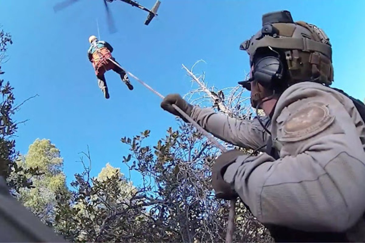 US Customs and Border Protection Aviation Enforcement Agent Scott Bowles secures the line as a hiker is hoisted up to his rescue team’s UH-60L Black Hawk, March 16, 2022, in the Huachuca Mountains in Arizona. Screenshot from US Customs and Border Protection’s Air and Marine Operations video.