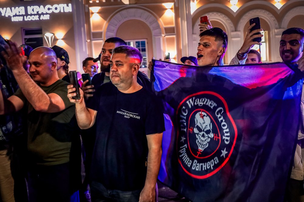 People shout and wave a flag of the Wagner Group military company to servicemen prior to their leaving an area at the headquarters of the Southern Military District.