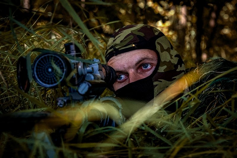 A Russian sniper looks from his position toward Ukrainian positions.