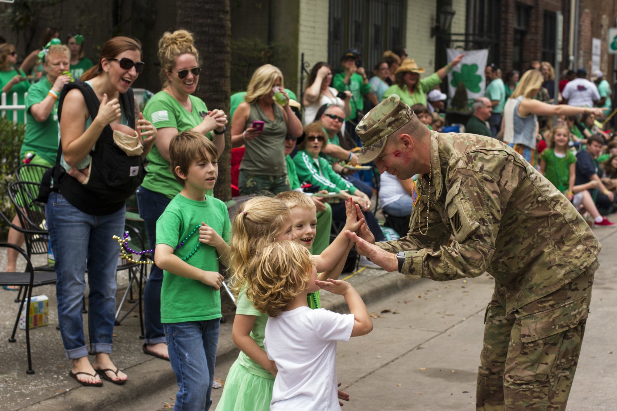 The commander of 3rd Combat Aviation Brigade, Col. Jeffrey Becker, high fives a group of children during the 192nd St. Patrick’s Day Parade March 17, 2016, in downtown Savannah. Photo by Spc. Scott Lindblom, 3rd CAB Public Affairs