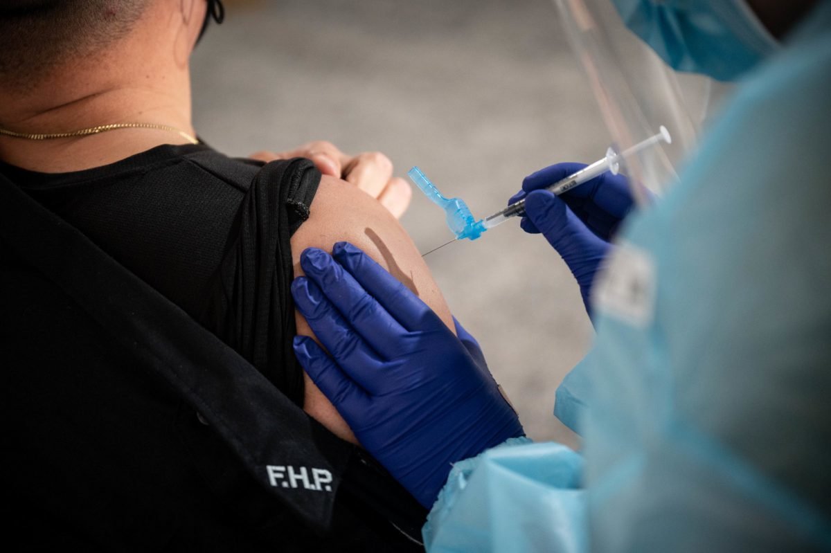 A Department of Defense medical technician vaccinates a Florida Highway Patrol member at the Community Vaccination Center at the Tampa Dog Track in Tampa, Florida, March 2, 2021. US Air Force photo by Master Sgt. Holly Roberts-Davis.