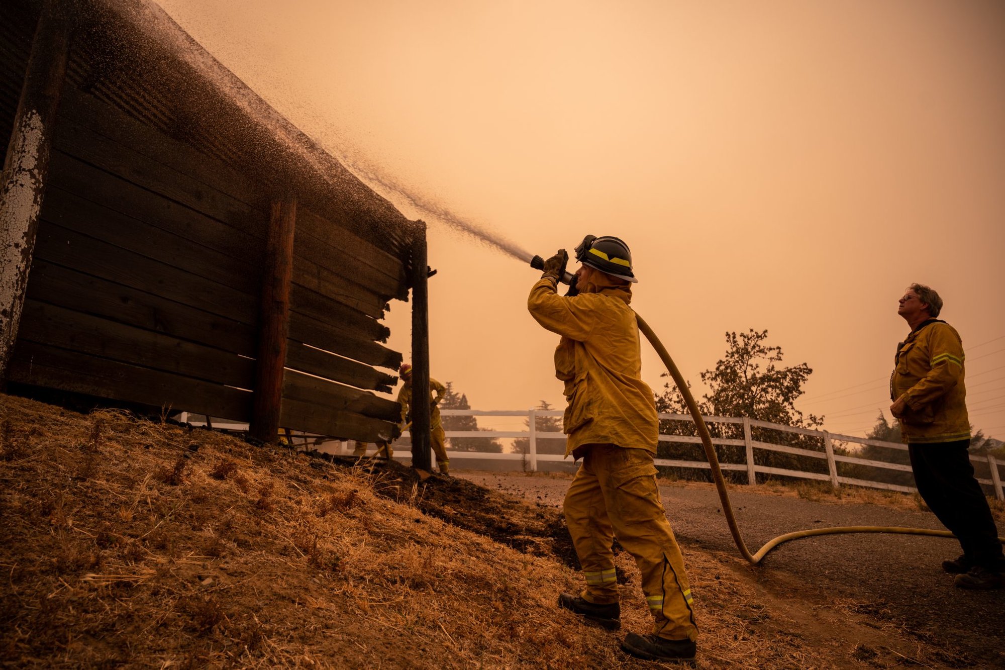 U.S. Air Force Airman 1st Class Ryan Girouex, 60th Civil Engineer Squadron firefighter, center, extinguishes a fire on a shed on Soaring Eagle Trail in Vacaville, California, Aug. 20, 2020. The 60th CES loaned 28 personnel and five trucks to aid in the fight against the LNU Lightning Complex Fire, a cluster of fires that forced tens of thousands of people to evacuate their homes. U.S. Air Force photo by Nicholas Pilch