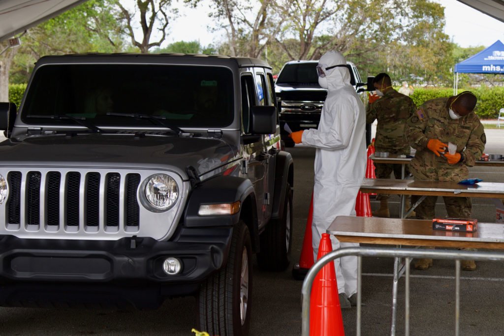 Florida National Guard Spc. Carlton Douge, with the Florida Medical Detachment, prepares to retrieve a sample from the patient at a COVID-19 Community Based Testing Site, March 19, 2020. South Florida’s first COVID-19 Community Based Testing Site is located at C. B. Smith Park. Photo by Army Sgt. Michael Baltz, courtesy of the Department of Defense.