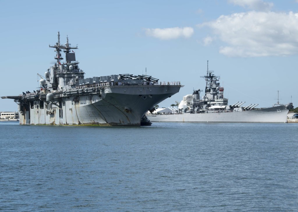 The amphibious assault ship USS Boxer (LHD 4) passes the Battleship Missouri Memorial while arriving at Joint Base Pearl Harbor-Hickam following a Western Pacific deployment, Nov. 13. Photo by Mass Communication Specialist 1st Class Holly L. Herline, courtesy of the U.S. Navy.