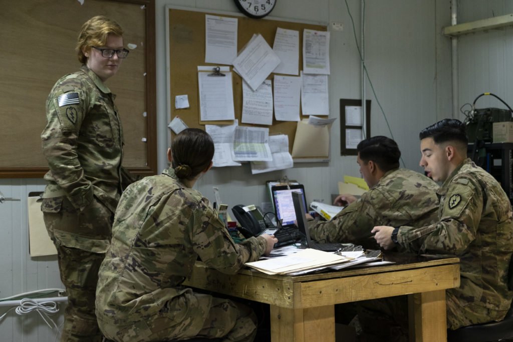 Monroe, left, talks with fellow medics in the office at the aid station after they receive an update on COVID situation in Kirkuk city. Photo by Kevin Knodell/Coffee or Die.